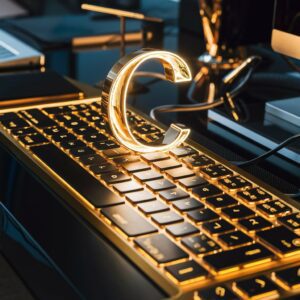 Luxurious keyboard with highlighted 'C' key surrounded by modern gadgets