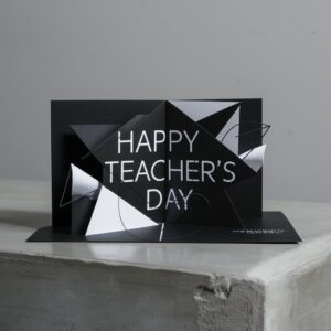 Minimalist black pop-up card with sharp white geometric elements and modern sans-serif text, set on a gray concrete background