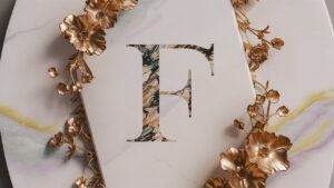 The name "F" is engraved in stunning white marble with gold accents for a timeless name DP.