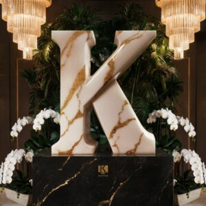 A majestic marble "K" illuminated by soft chandelier lights, ideal for a luxurious name DP.