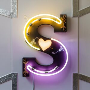 Playful neon 'S' logo shifting from yellow to purple, adorned with a heart glow and a shimmering butterfly." 